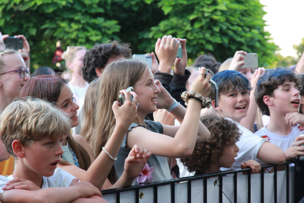 Teenagers at an outdoor event filming on their phones